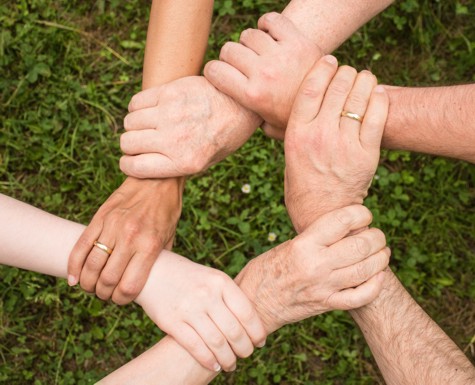 Picture of six crossed hands holding one arm each.